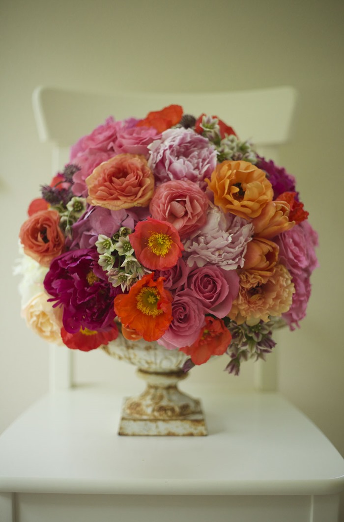A circular Alicia Schwede compote floral arrangement in pink, orange, and red