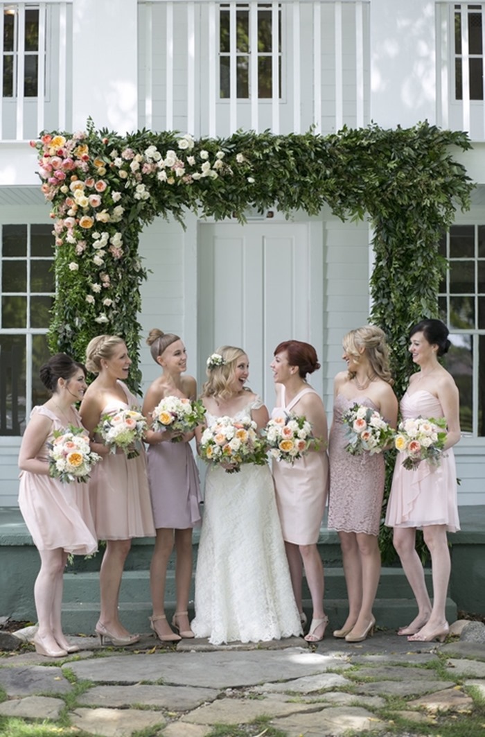 a bride and bridesmaids stand under a floral arch for Botanical Brouhaha Expert Panel 75