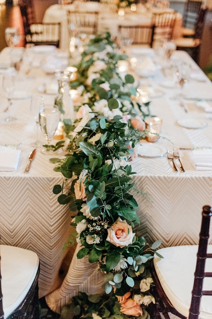 A table centerpiece using custom garlands spills over a table at a wedding reception