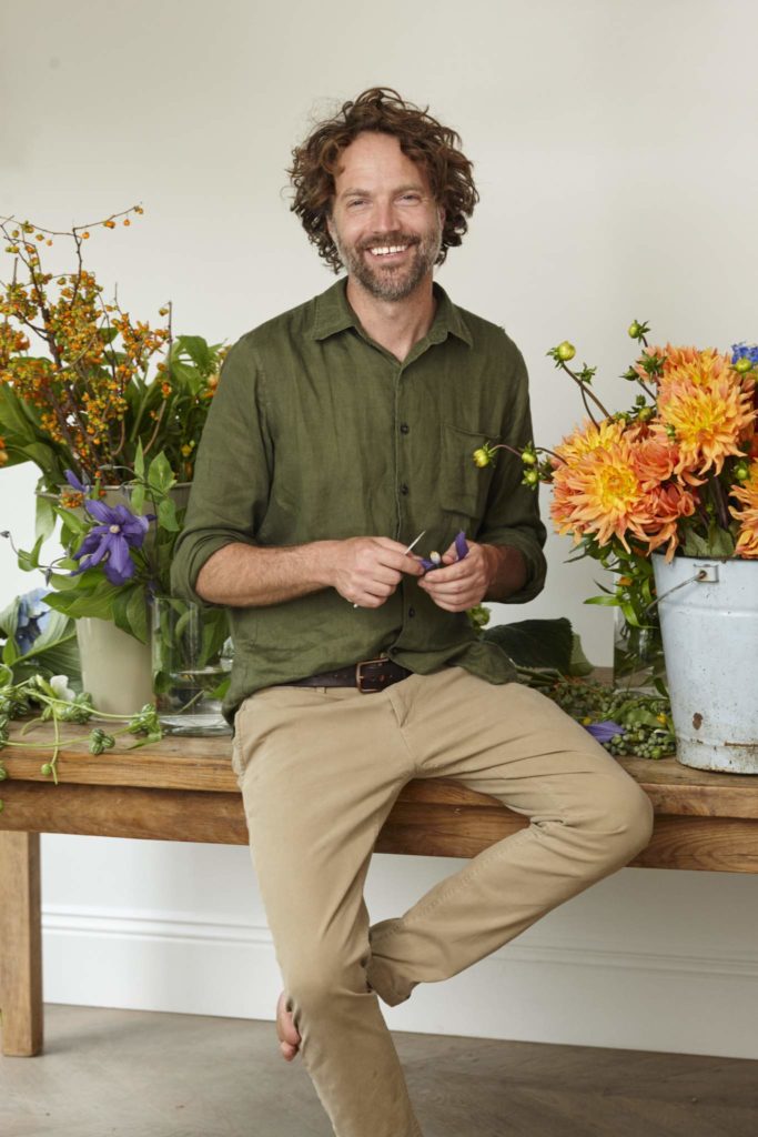 Robbie Honey sits on a table with fresh flower buckets
