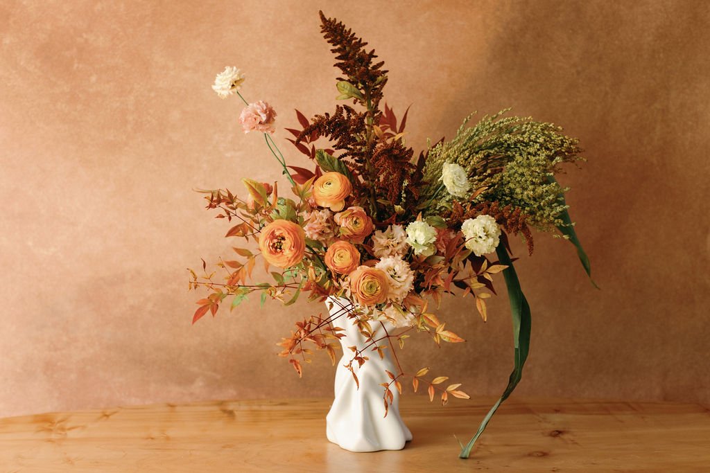 The Twist No. 1 vase designed by Sullivan Owen holds an autumn bouquet of orange and burgundy flowers designed by Native Poppy