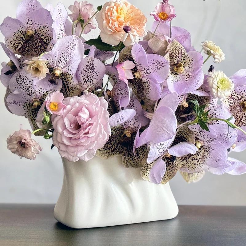 The Envelope No. 1 vase designed by Sullivan Owen holds a lush bouquet of lavender orchids, japanese anemones, and garden roses